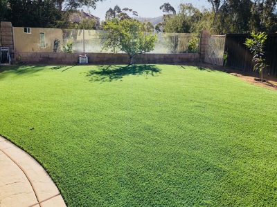 Backyard with artificial grass and white fence surrounding it